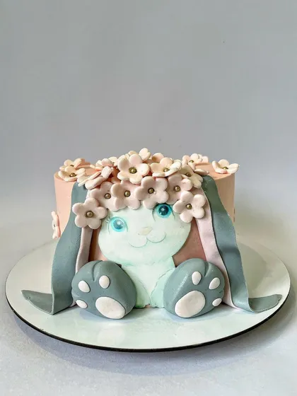 Some bunny is turning one! This adorable bunny cake features a hand-molded fondant bunny face with a crown of delicate sugar flowers. It's a sweet and gentle theme for a little one's celebration.