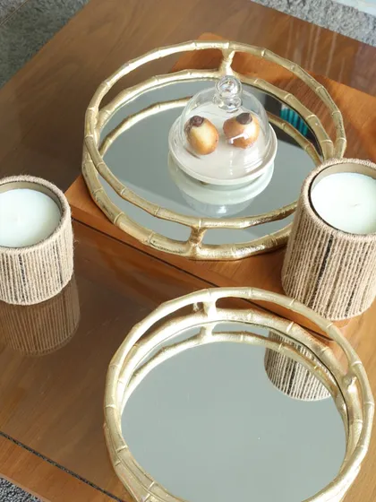 A pair of our round bamboo-style mirror trays, styled with candles and a cloche. They are perfect for creating a layered and sophisticated look on a coffee table or console.