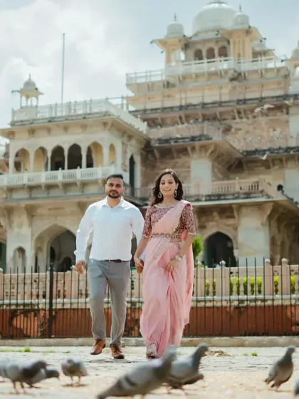A confident walking shot towards the camera, with Albert Hall and the famous pigeons creating a classic Jaipur scene. This photo is full of style and energy.