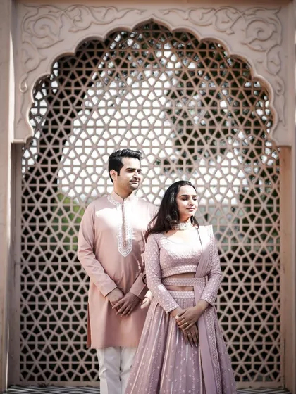 A stylish pre-wedding portrait using a carved stone screen as a backdrop. The intricate details of the screen complement the couple's elegant attire.