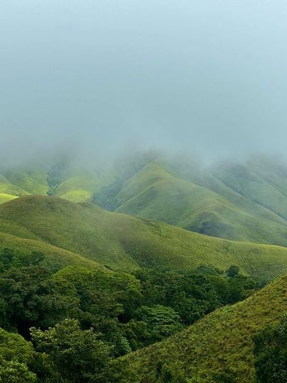 Sunlight breaking through the clouds to illuminate the green valleys of Kudremukha.