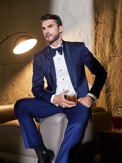 A moment of quiet contemplation. The navy tuxedo, paired with a classic drink, evokes an atmosphere of sophistication and old-world charm, updated for the modern gentleman.