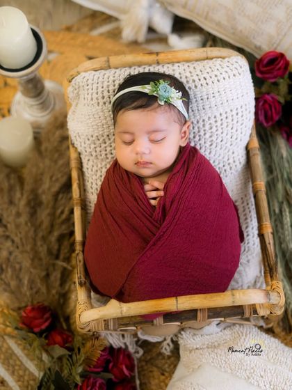 A cozy and content newborn wrapped in a beautiful red swaddle. This pose highlights the baby's delicate features and peaceful sleep.