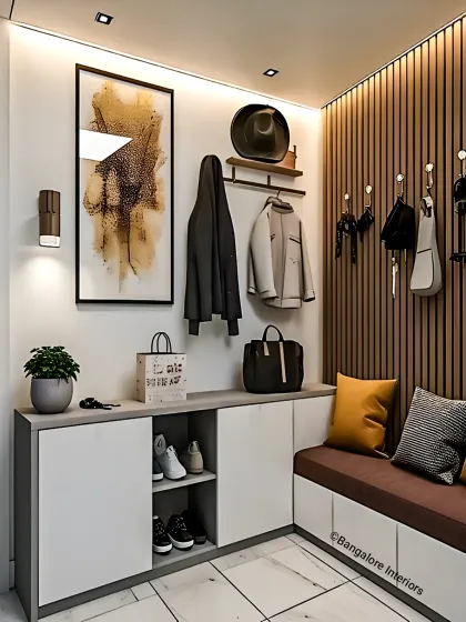 This entryway design features a comfortable bench with shoe storage cabinets below. We included hooks for coats and bags on a wood-paneled wall, creating a functional and organized drop zone.