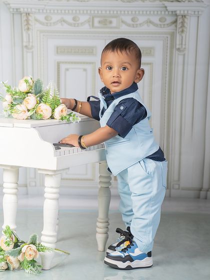 A star in the making, playing tunes of pure magic. This little boy looks sharp in his vest and trousers as he stands at the miniature piano.