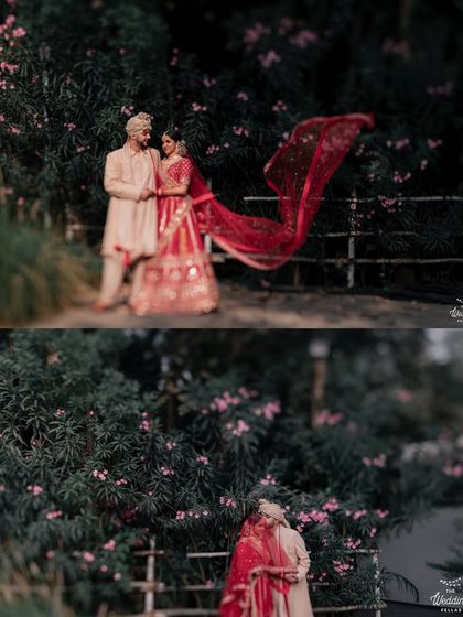A dynamic shot of a bride's red veil flowing in the breeze. The dark green foliage behind them makes the colors of their outfits stand out beautifully.
