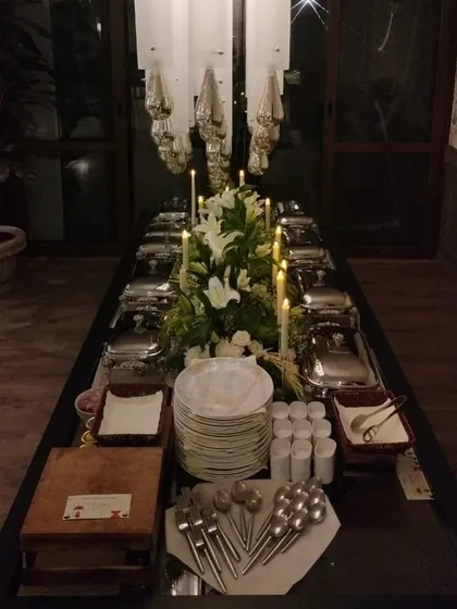 A long shot of the candlelit buffet table, showing the complete setup with plates, cutlery, and serving dishes ready for guests.