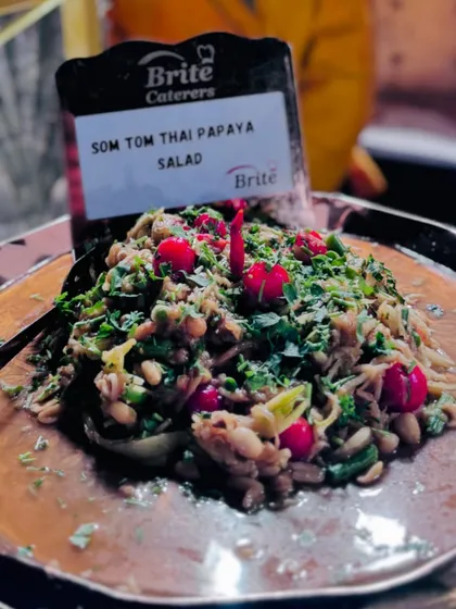 A close-up of the vibrant and fresh Thai Papaya Salad, garnished with cherry tomatoes and peanuts.