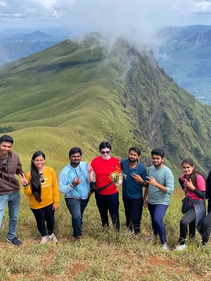 A happy group posing with peace signs at the Nethravathi summit, celebrating their achievement.