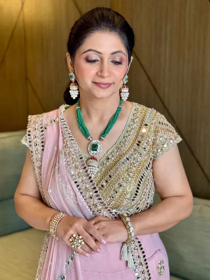 A serene portrait. The soft pink and gold tones in her makeup perfectly complement her beautiful saree and emerald jewelry.