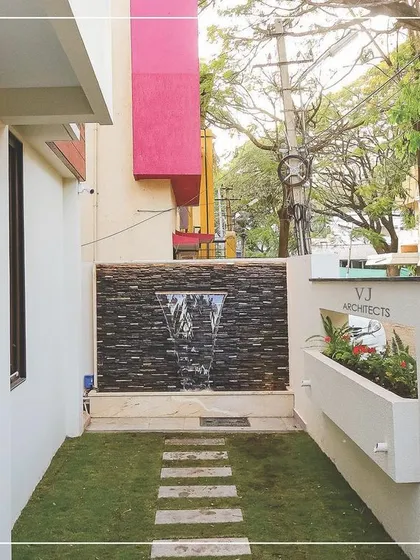 Even compact urban spaces can become serene retreats. For this Hubli residence, we designed a tranquil side yard featuring a stone-clad water feature, a simple lawn with stepping stones, and an integrated wall planter, proving that beautiful landscape design is possible on any scale.