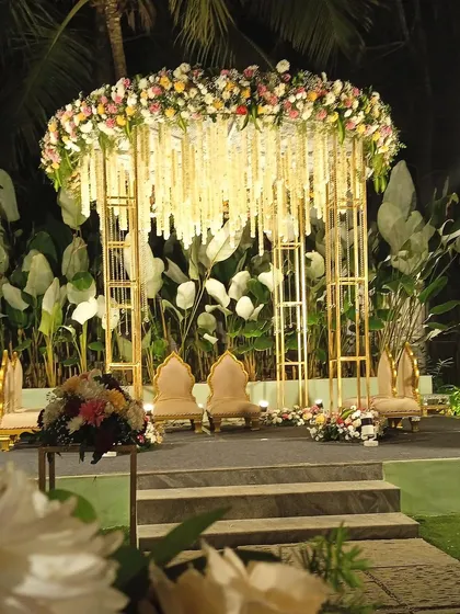 Another angle of this stunning modern mandap. The clean lines of the golden frame contrast beautifully with the lush tropical foliage in the background, perfect for an evening ceremony.