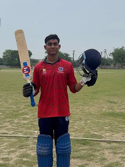 A player raises his bat and helmet to celebrate a magnificent century in a league match. This is a moment of triumph, a direct result of relentless hard work and dedication in training.