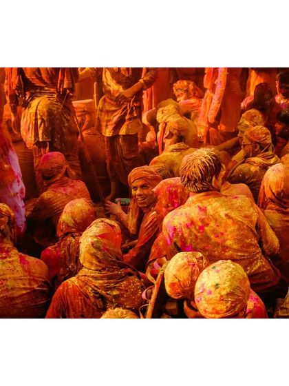 A high-angle view of the Holi celebrations, showing the dense crowd covered in a blanket of yellow and orange powder.