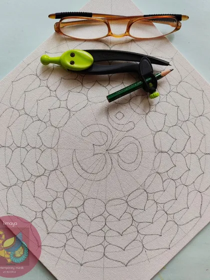 A different design for a Vastu Om, this one with a lotus petal or heart-shaped border. The sketch shows the geometric precision required before the painting process can begin.