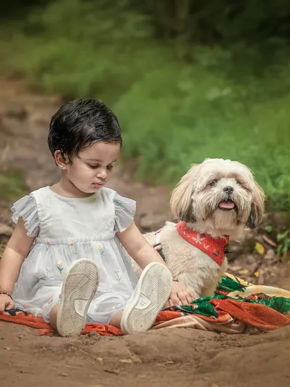 There is a special magic when a child and their furry friend share a quiet moment. This outdoor portrait captures the gentle, unspoken bond between a little girl and her dog on a rustic forest path.