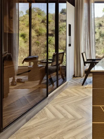 This spacious walk-in closet at Terra features warm lighting and a central island with integrated drawers. Clothes are displayed on built-in shelves and hanging rods, creating a luxurious and highly organized space that is a pleasure to use.