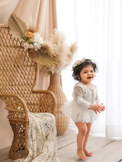 A moment of joy in a boho paradise. This little girl's happy expression is perfectly framed by the wicker peacock chair and pampas grass. This setup is a favorite for its warm and natural feel.