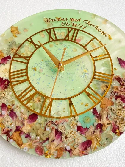 A full view of the beautiful 12-inch wall clock with preserved orchids and other flowers. The couple's names and wedding date are subtly placed at the top.