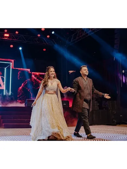 Making a grand entrance at their Sangeet. The bride shines in a shimmering lehenga by I-sa by Dolly Wahal, while the groom looks sharp in a textured bandhgala by Shantanu & Nikhil.