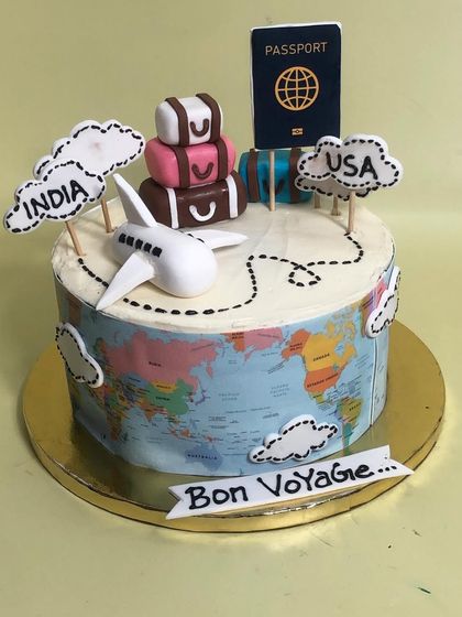 A 'Bon Voyage' cake perfect for someone embarking on a new journey. This travel-themed cake features an edible world map wrap, a fondant passport, luggage, and an airplane charting a course from India to the USA.