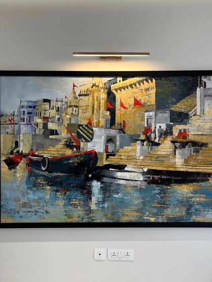 The 'Banaras Ghat' painting installed in a client's home, illuminated by an art light. Proper lighting can dramatically enhance the colors and details of a painting.