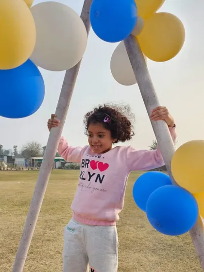 Pure, simple fun. A young girl plays on a swing set decorated with balloons during a party.