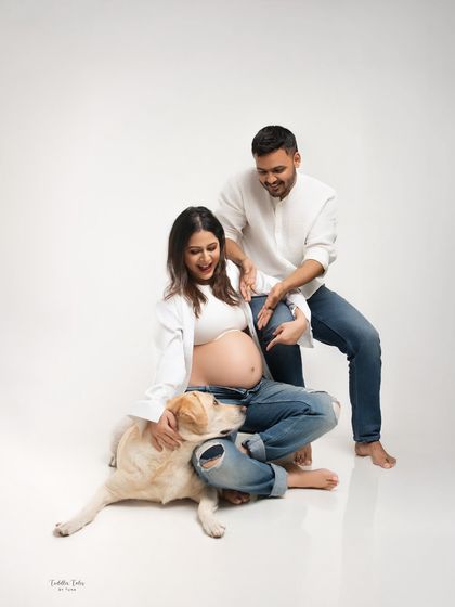 The couple shares a laugh as their dog affectionately nudges the baby bump. These candid moments add so much personality to a session.