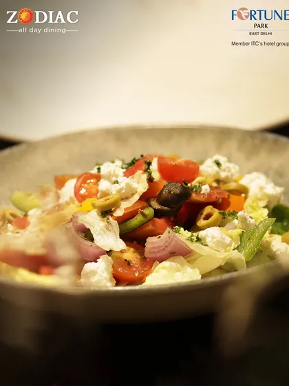 A fresh and vibrant Greek salad from our Zodiac menu, tossed with feta cheese, olives, and a light vinaigrette.