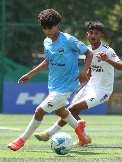 A player shields the ball from a defender, showcasing strength and control during a competitive U-17 league match.