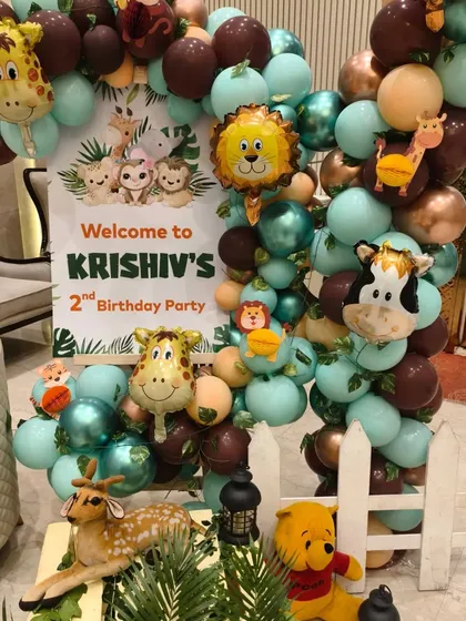 The welcome corner for the jungle party, featuring a personalized sign, a balloon garland with animal foils, and cute stuffed animals.