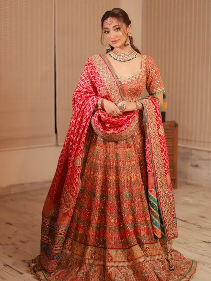 A full-length shot showcasing a royal bridal look. The makeup is designed to feel regal, matching the heavy embroidery of the lehenga and the statement jewelry.