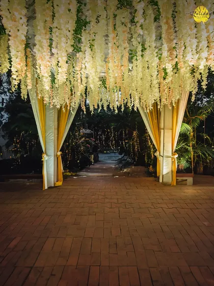 An enchanting entrance with a canopy of hanging white and yellow flowers welcomes guests into the main event area, setting a festive and elegant tone from the start.