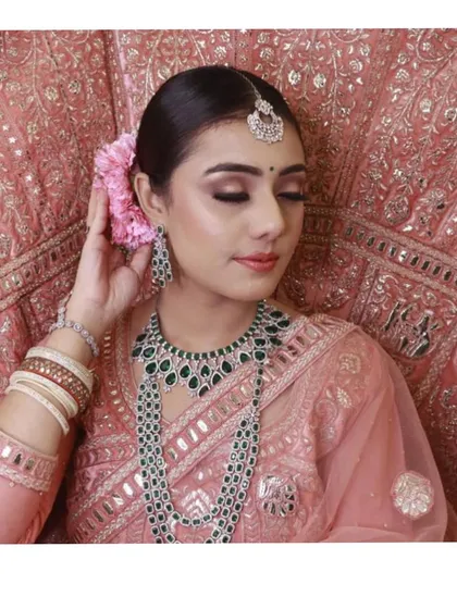 A close-up showcasing the beautiful emerald jewellery paired with the peach-pink lehenga. I can help you find the perfect rental jewellery to complement any outfit.