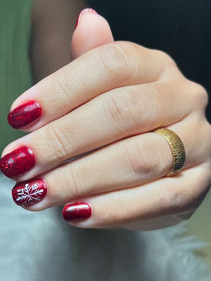 A simple and elegant Christmas design. This look features a sparkling red gel polish with a single accent nail adorned with a delicate white snowflake.