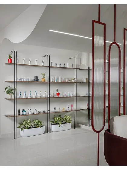 This retail display area features minimalist black metal shelving against a clean white wall. The design is intentionally simple to allow the products to stand out, with integrated planters adding a touch of natural softness.