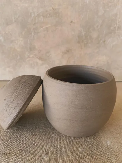 A raw and unrefined lidded jar, showcasing the simple beauty and authenticity of unglazed clay.