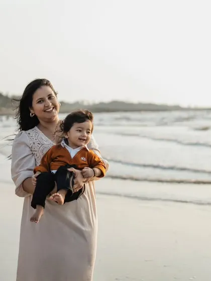 A beautiful portrait of a mother and her son on the beach. Her smile and the peaceful ocean backdrop create a serene and happy memory.