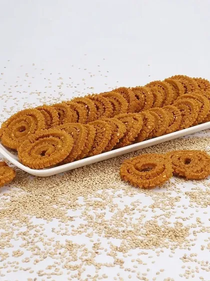 A clean, organized presentation of chakli snacks on a long platter, with sesame seeds scattered around to highlight a key ingredient.
