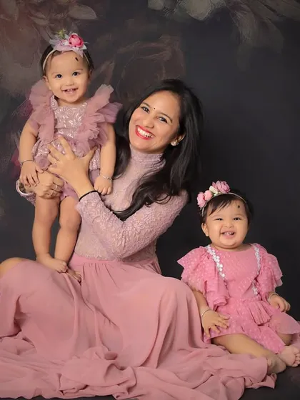 A beautiful mother and her twin daughters. The flowing pink gown and the girls' happy faces create a stunning and heartwarming portrait.