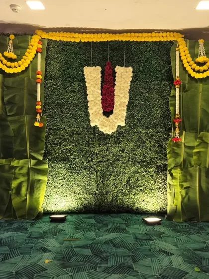 We create authentic South Indian themed decorations, perfect for a Roka ceremony. This backdrop uses a wall of fresh banana leaves, a faux grass panel, and marigold garlands for a traditional and natural feel.
