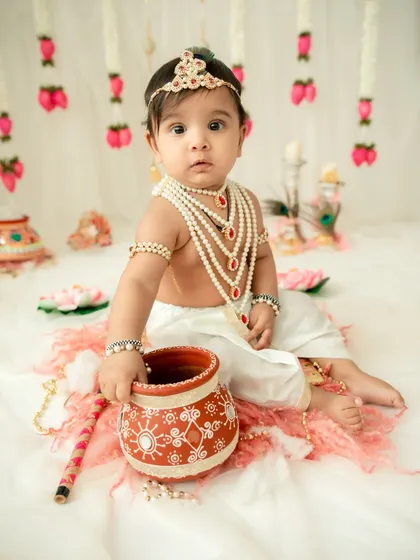 A curious little Krishna with his pot of butter. The soft lighting and traditional props create a timeless and adorable portrait.