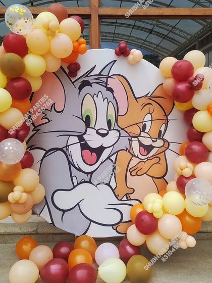 A fun Tom and Jerry themed circular backdrop surrounded by balloons in a neutral color palette.