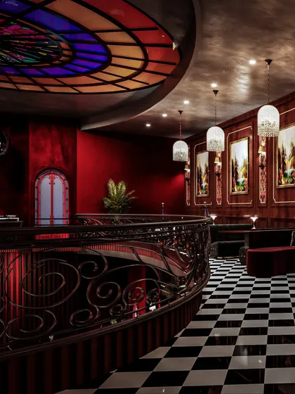 This view shows the upper level of the bar, with its ornate iron railing and a stunning stained-glass ceiling feature.