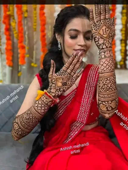 A stunning bride in a red saree posing with her elegant bridal mehandi.