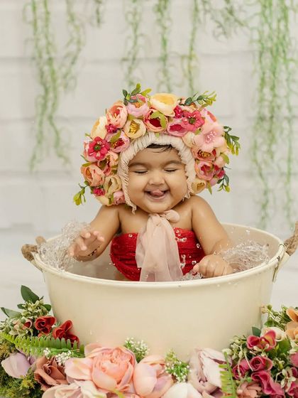 A playful moment with her tongue out, this little one is having the best time in her floral bath.