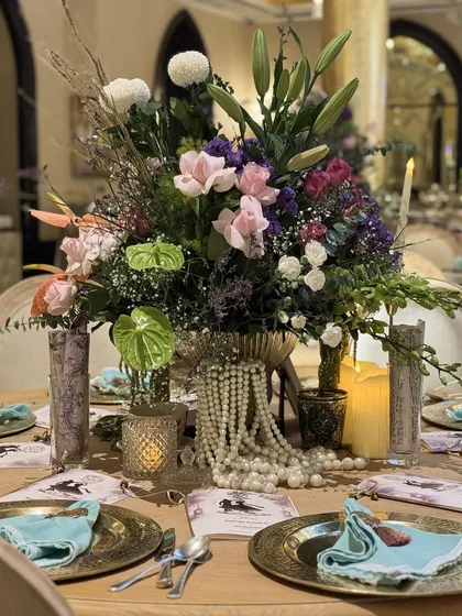 A lavish tablescape featuring a large floral centerpiece, strings of pearls, and custom-printed menus, creating a look of pure opulence.