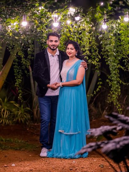 A full-length portrait of a couple under a canopy of hanging lights in our lush garden.