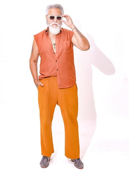 The model adjusts his sunglasses, adding a touch of cool and character to this bright and energetic fashion shot.