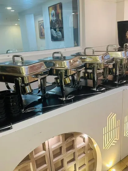 A modern, lit buffet counter with stainless steel chafing dishes, perfect for contemporary weddings and corporate events.